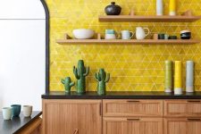 a bold boho kitchen with rich stained cabinets, black countertops, open shelves, a bold yellow tile accent wall