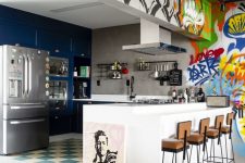 a bold kitchen with blue cabinets, stainless steel appliances and a white kitchen island, bold graffiti walls and a hood