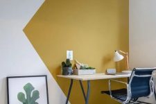 a bold modern working nook with a mustard and white color block wall, a lightweight desk, a black chair and a greenery print