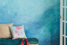 a bright space with a beautiful blue watercolor wall, a refined dark green bench, a woven rug and some pillows is lovely