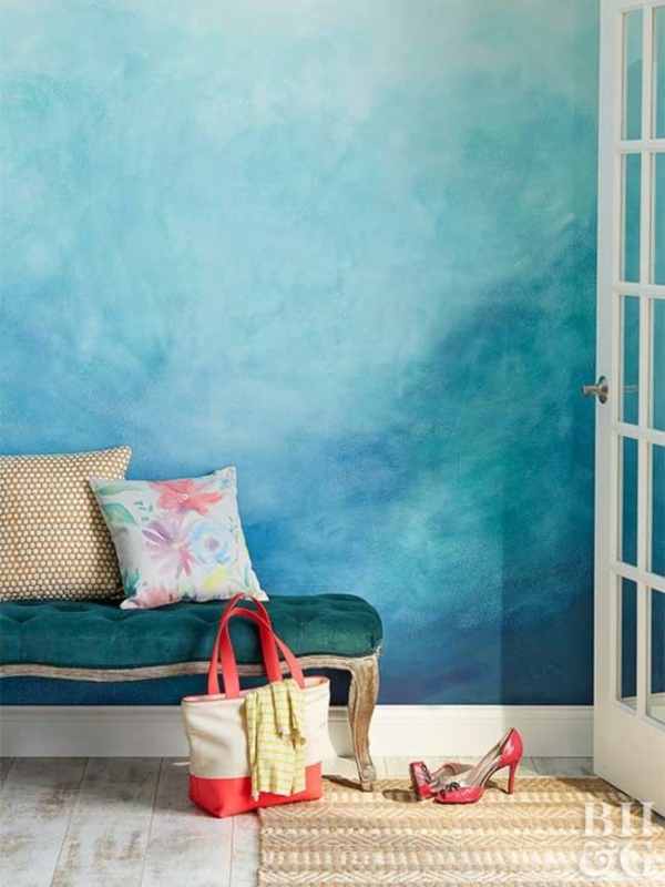 a bright space with a beautiful blue watercolor wall, a refined dark green bench, a woven rug and some pillows is lovely