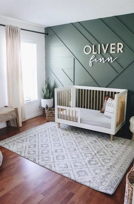 a chic contemporary nursery with a green paneled wall, mid century modern furniture, neutral textiles and potted greenery