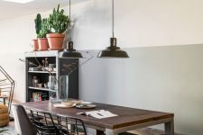 a chic industrial dining space with a grey storage unit, a wood and metal table, black metal chairs and stools and black pendant lamps