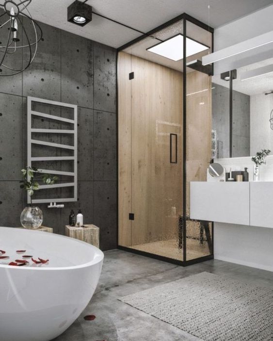 a contemporary industrial bathroom with a concrete floor, concrete panels on the walls, a sleek white vanity and a shower space enclosed in glass
