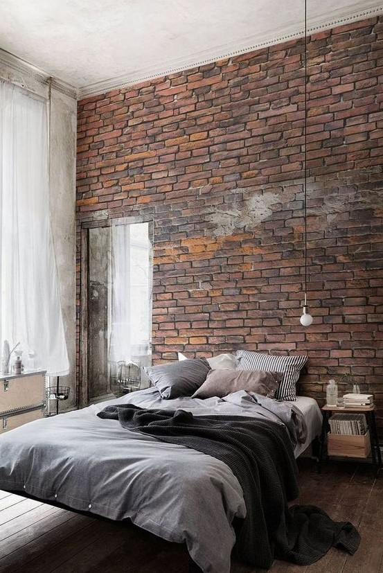 a contemporary industrial bedroom with a faux red brick wall, a floating bed, nightstands, a mirror and pendant bulbs