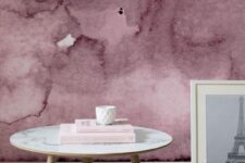 a cool space with a pink watercolor wall, a round table, a grey faux fur rug, an artwork is a stylish and bold nook