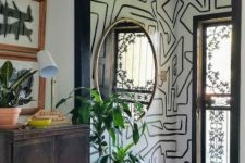 a creative entryway with a graffiti nook, a bold rug, a dark-stained dresser, a round mirror and potted plants is wow