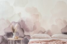 a delicate bedroom with a blush and lilac watercolor wall, a bed with blush bedding, a side table and grass in a vase