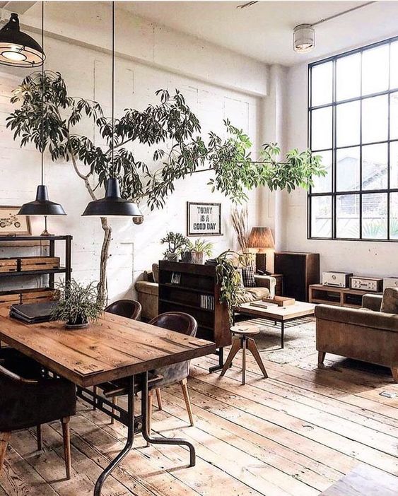 a dining space with an industrial feel, with a metal and wood dining table, leather chairs, a metal shelving unit and metal pendant lamps