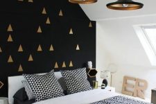 a gorgeous black and gold geometric pattern accent wall plus black and brass pendant lamps that echo with it