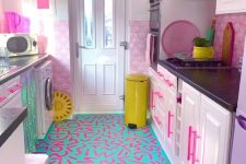 a light pink kitchen with hot pink handles, a bold turquoise and pink graffiti floor and bold yellow touches for more fun