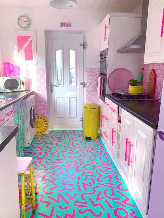 a light pink kitchen with hot pink handles, a bold turquoise and pink graffiti floor and bold yellow touches for more fun