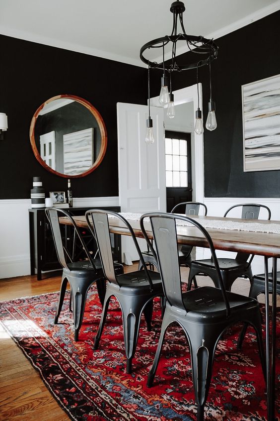 a modern dining room with a black console table, dining table with hairpin legs, black metal chairs, a chic chandelier