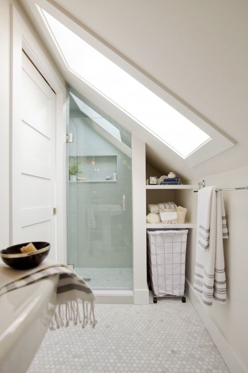 a neutral attic bathroom with a shower space done with aqua tiles, penny marble tiles on the floor and a large skylight