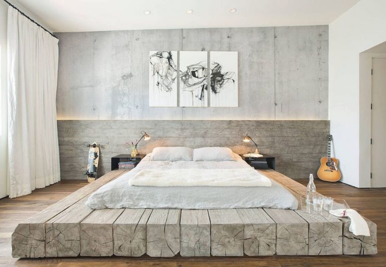 a neutral industrial bedroom with concrete and whitewashed wood walls, a wooden slab platform bed, an artwork, black nightstands and metal lamps