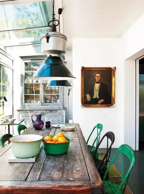 a rustic vintage sunroom with shabby chic furniture, metal chairs, mismatching pendant lamps and a vintage portrait