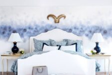 a sophisticated bedroom with a grey watercolor wall, a white bed with blue bedding, a hot pink upholstered bench, refined nightstands and table lamps