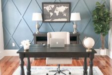 a stylish farmhouse home office with a blue geometric accent wall, dark furniture, a creamy chair, a printed chair and a statement plant