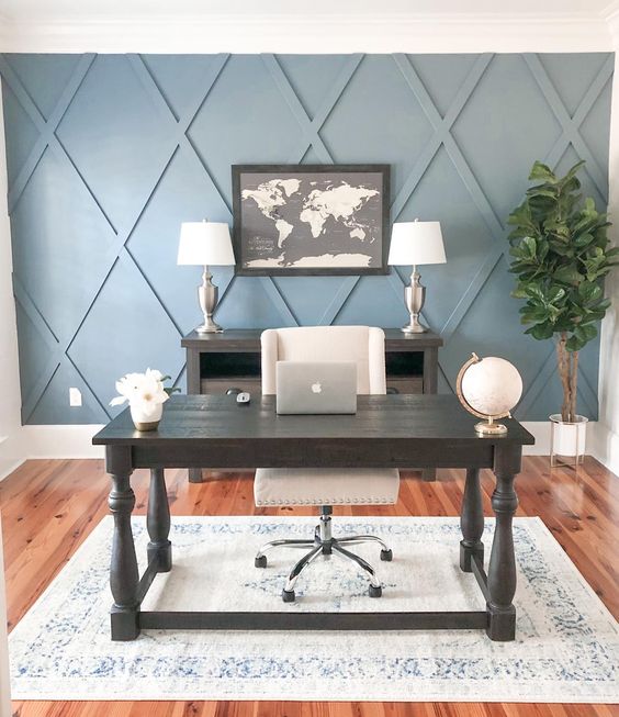 a stylish farmhouse home office with a blue geometric accent wall, dark furniture, a creamy chair, a printed chair and a statement plant