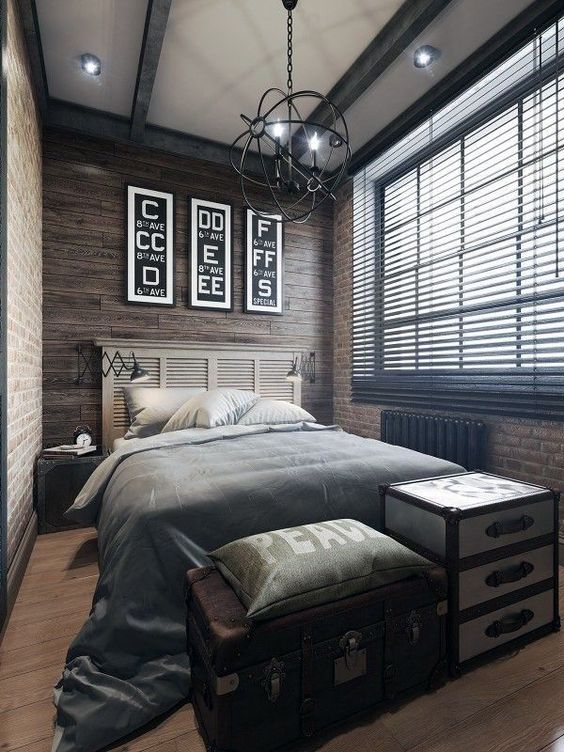 a stylish industrial bedroom clad with wood and brick, with wooden beams and a cool sphere chandelier, a bed with a shutter headboard, neutral bedding and chests for storage