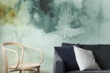 a stylish living room with a green watercolor wall, a black sofa with black pillows, a stained chair is a cool space