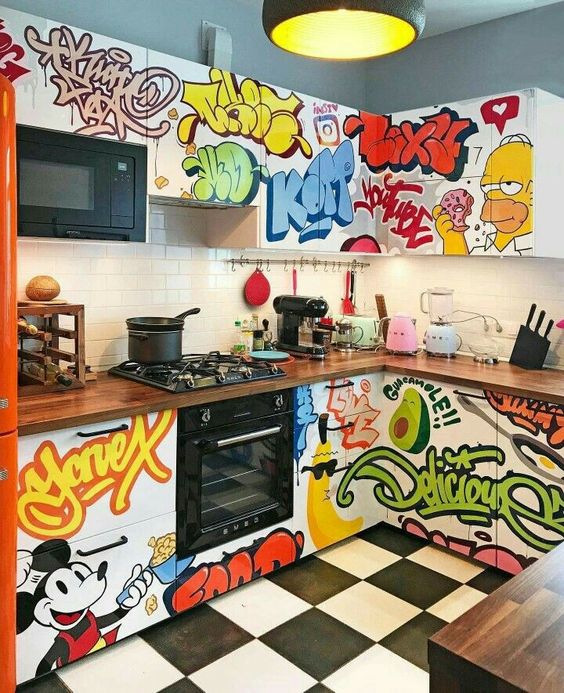 a super colorful and crazy graffiti kitchen with a white subway tile backsplash and built in appliances plus a black pendant lamp