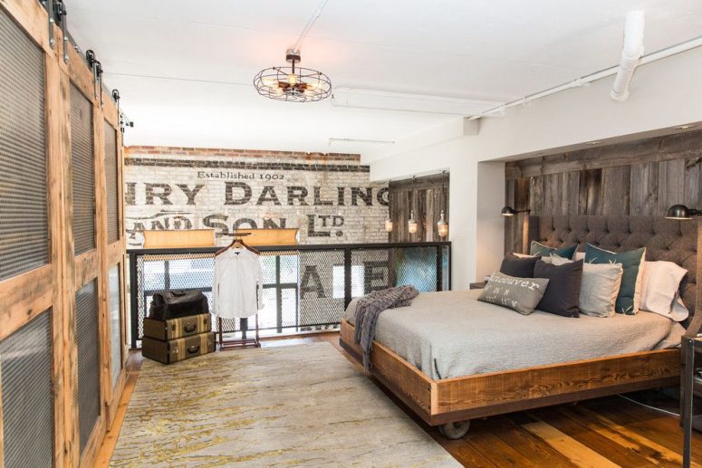 a vintage industrial bedroom with a wooden bed on casters, a reclaimed accent walls, chicken wire railing, suitcases for storage and a corrugated metal wardrobe