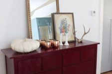 a vintage-inspired sideboard painted burgundy for the fall, with antlers and a pumpkin