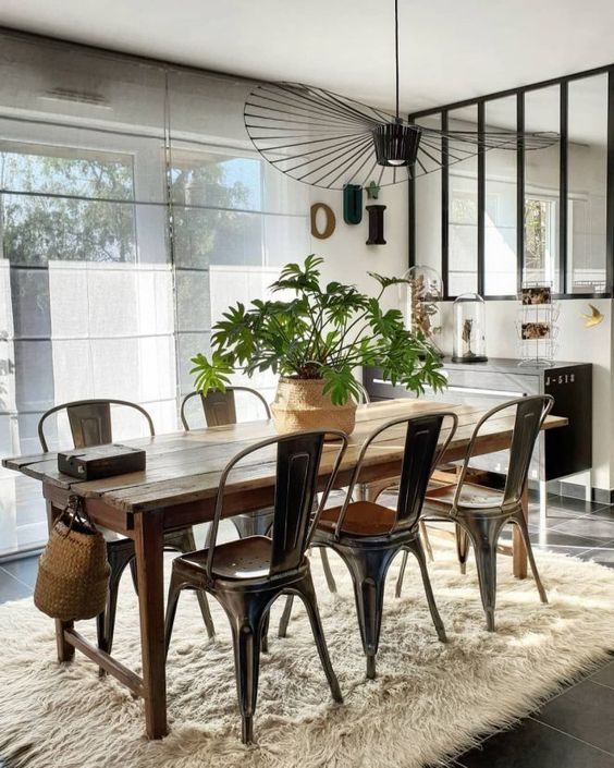 a welcoming modern dining room with a black credenza, a stained dining table, black metal chairs and a black chandelier