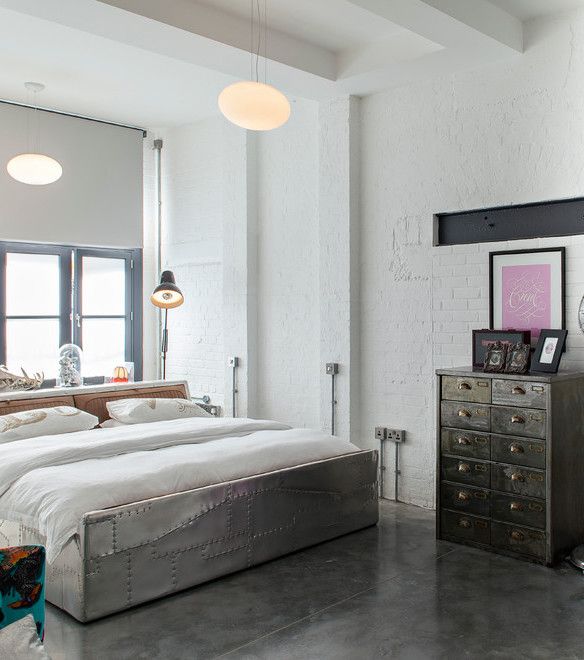 a white industrial bedroom with brick walls, a catchy metal bed, a vintage file cabinet for storage and pendant lamps