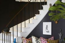 an artistic foyer with black walls, a graffiti artwork, colorful pillows and a potted plant is amazing