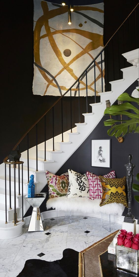 an artistic foyer with black walls, a graffiti artwork, colorful pillows and a potted plant is amazing