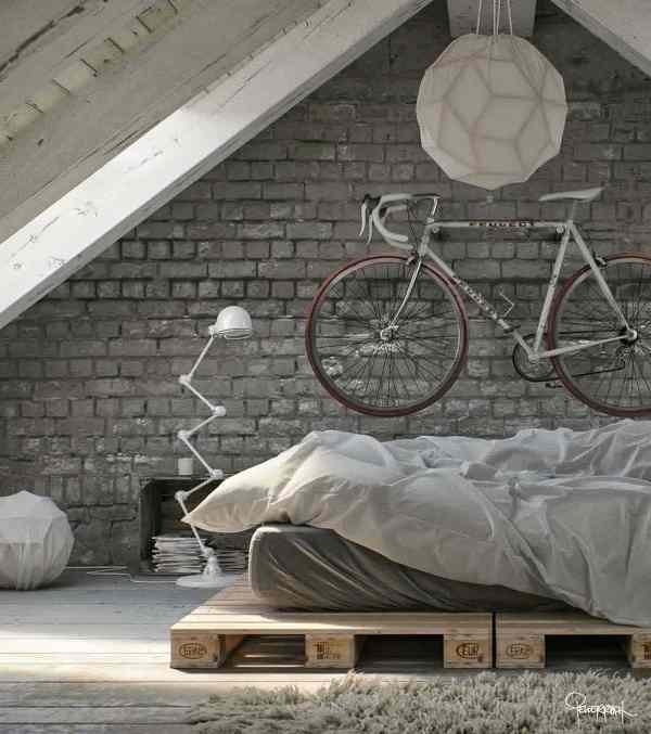 an attic bedroom with a brick accent wall, a pallet bed with neutral bedding, a quirky table lamp and a bike over the bed as decor