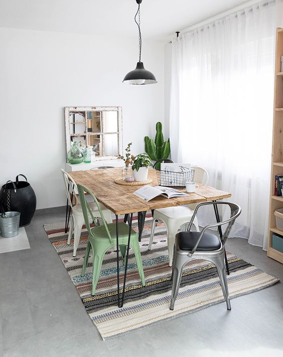 an eclectic dining zone with a hairpin leg table, mismatching metal chairs, a black pendant lamp and potted plants