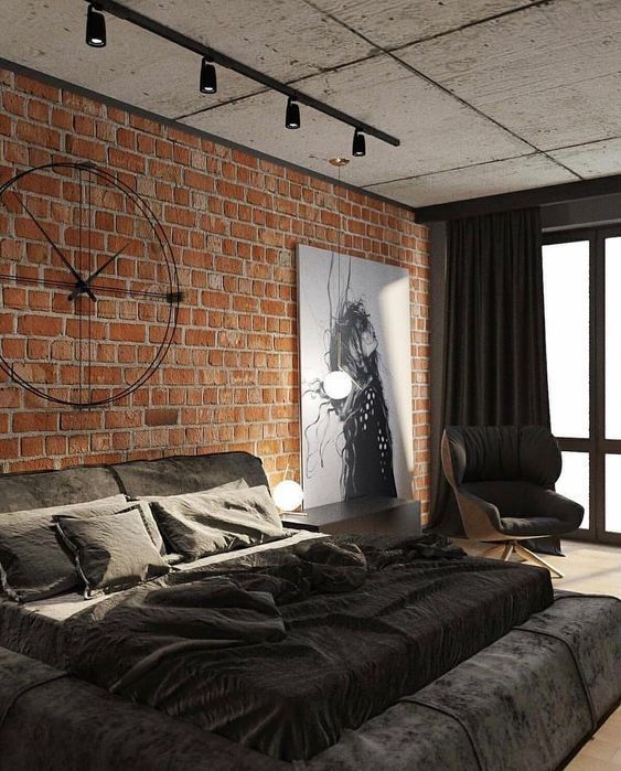 an elegant industrial bedroom with a red brick accent wall, a black upholstered bed with black bedding, a creative metal clock and lights