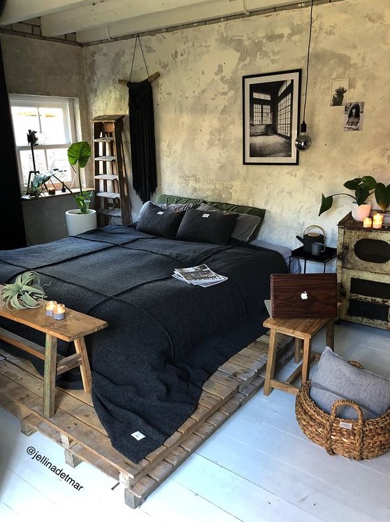 an industrial bedorom with shabby chic walls, a pallet bed, simple wooden furniture and dark bedding
