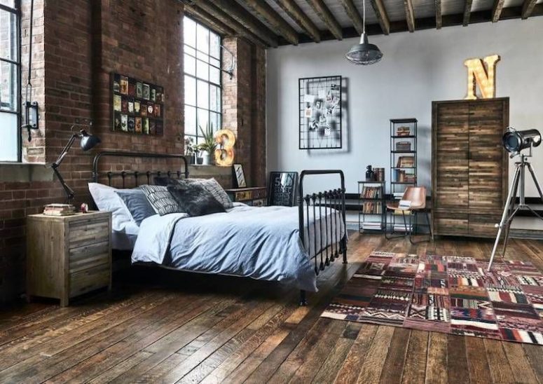 an industrial bedroom with a brick wall, a ceiling with beams, a metal bed, wooden nightstands, metal shelving units and marquee lights