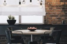 an industrial dining room with brick walls, a round table, black chairs, pendant bulbs and a potted plant is amazing