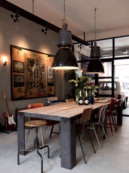 an industrial dining space with a sturdy wood and metal table, mismatching vintage chairs, black pendant lamps and a large artwork