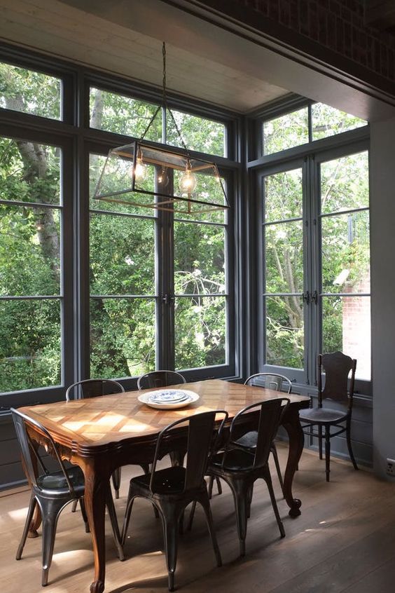 an industrial dining space with a vintage refined dining table, metal chairs and a metal frame pendant lamp