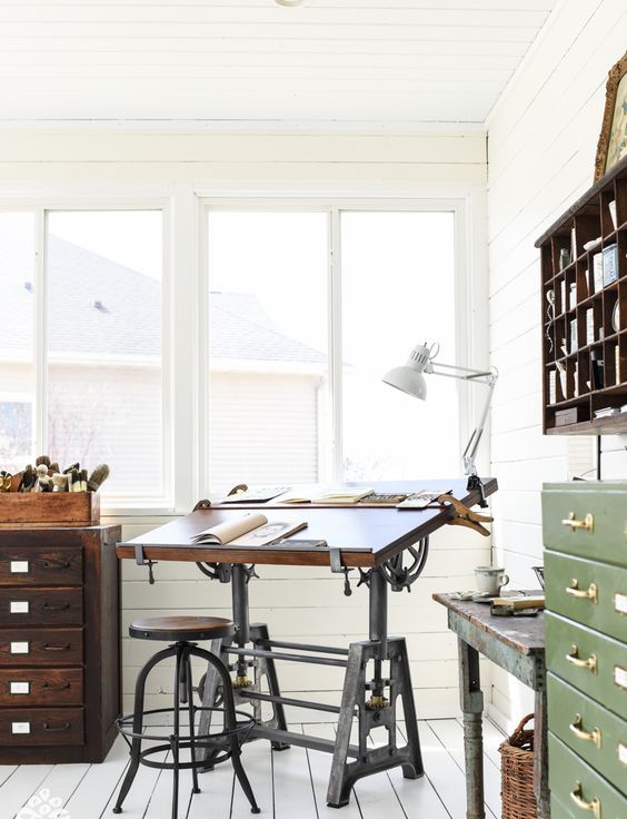 an industrial home office with white planked walls and the floor, a metal and wooden desk and a matching stool, vintage file cabinets of wood and metal