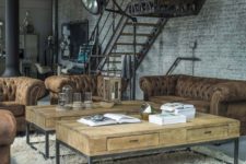 an industrial living room with whitewashed brick walls, leather tufted sofas, wood and metal coffee tables