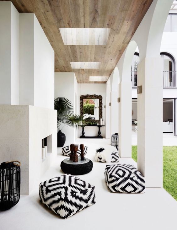 an outdoor patio with a concrete fireplace with pillar candles, black and white poufs and black candle lanterns