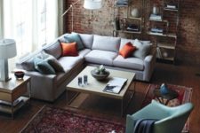 brick walls, rich-colored wood floors, an industrial piping open shelving unit and a metal and wood coffee table
