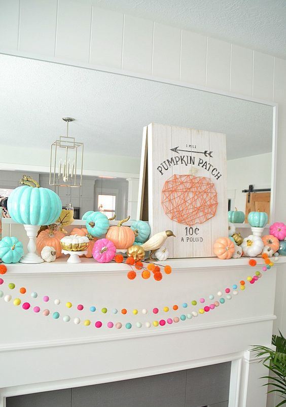 a Halloween mantel with bright felt garlands, colorful pumpkins and pompoms and a yarn sign