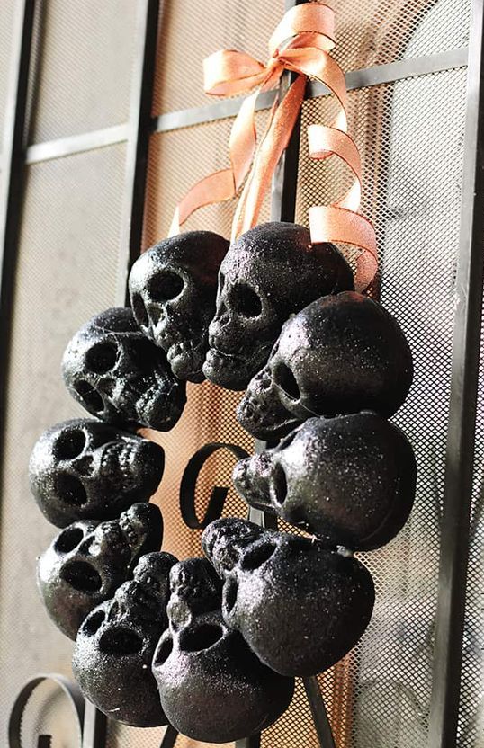 a Halloween wreath of glitter black skulls and an orange bow on top is a classic decor idea for Halloween