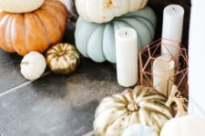 a Thanksgiving fireplace with stacked heirloom pumkins and pilalr candles in lanterns and without them