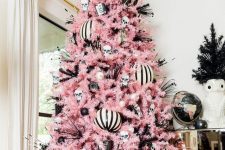a black, pink and white Halloween tree with large ornaments, skulls, witches’ legs and bottle cleaners