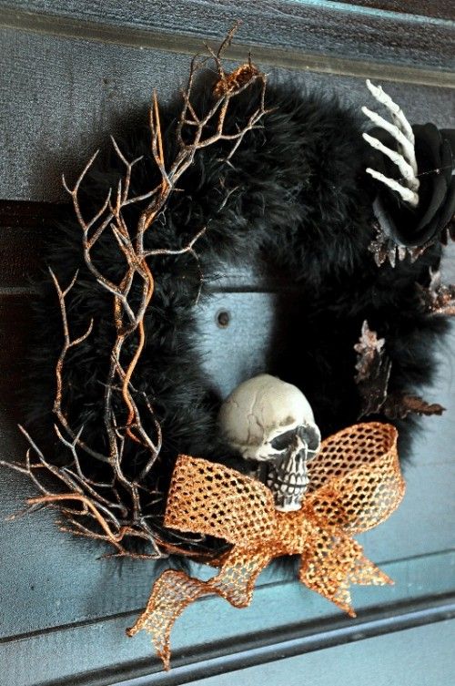 a bold Halloween wreath of faux fur, gilded twigs, a skeleton hand, a skull and an orange mesh bow is amazing