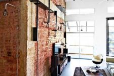 a brick wall and exposed black pipes make the space feel industrial and add interest to it